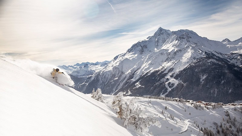 Balcon avec vue sur montagnes enneigées et skieur en action.